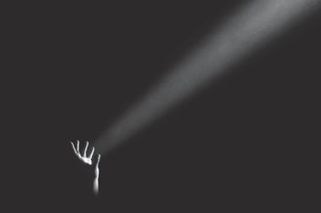 A hand projecting light into darkness